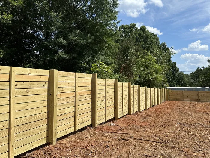 New pressure treated privacy fence on a cleared back yard lot